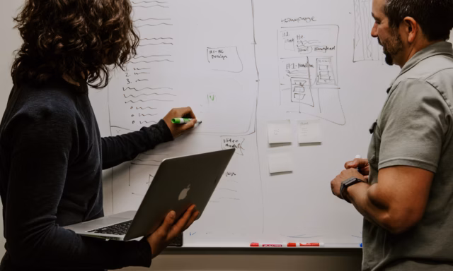 Besprechung am Whiteboard mit Wireframes/Skizzen für ein individuelles Design.